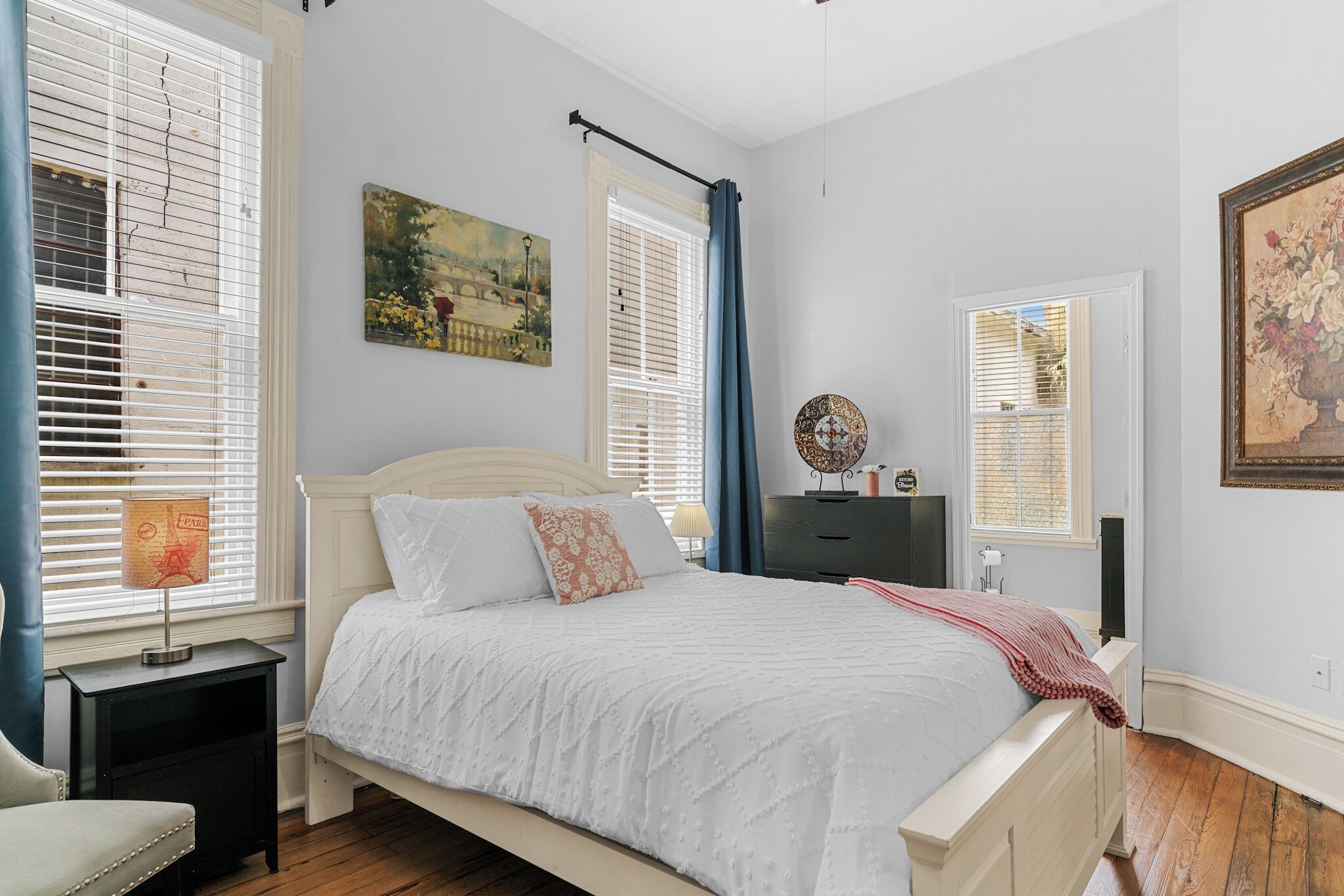 Une chambre à coucher comprenant un lit, des tables de chevet, une commode et des œuvres d’art accrochées aux murs.