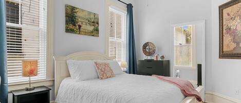 Une chambre à coucher comprenant un lit, des tables de chevet, une commode et des œuvres d’art accrochées aux murs.