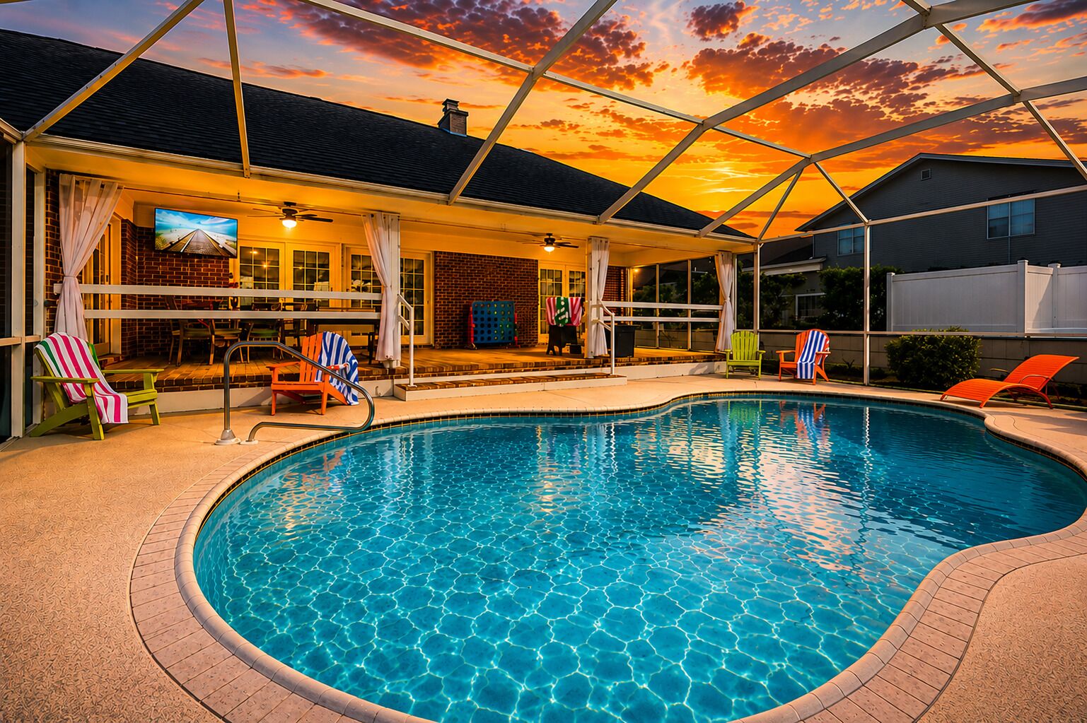 A swimming pool with a covered patio area, lounge chairs, and a sunset view.