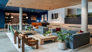 A modern lounge area with a bar, seating arrangements, and a large window. - Cozy 1-bedroom apartment in SF with AC, fitness room (San Francisco)