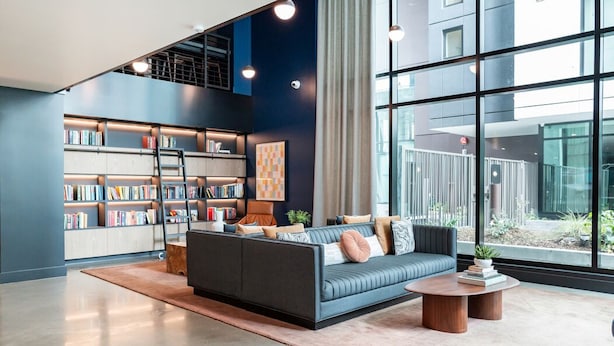 A modern lounge area with a sofa, coffee table, and bookshelves. - Cozy 1-bedroom apartment in SF with AC, fitness room (San Francisco)