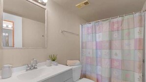 A bathroom with a white sink, mirror, and toilet. - Estero Beach and Tennis 1202 (Fort Myers Beach)