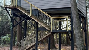 A treehouse with a wooden exterior, a staircase, and a small platform with railings. - Secluded Treehouse w/ River & Trail Access (Deerbrook)