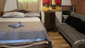 A room with a bed, a sofa, a wooden floor, and a wall-mounted air conditioning unit. - Paradise point camping - Dome 1 (Tamarindo)