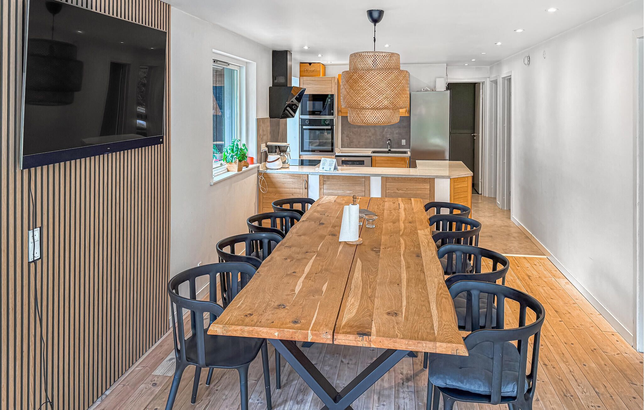 Una cucina moderna con isola centrale, tavolo da pranzo in legno e sedie nere.