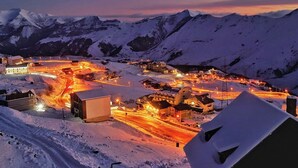Une ville de montagne enneigée au crépuscule, avec des rues et des bâtiments illuminés.