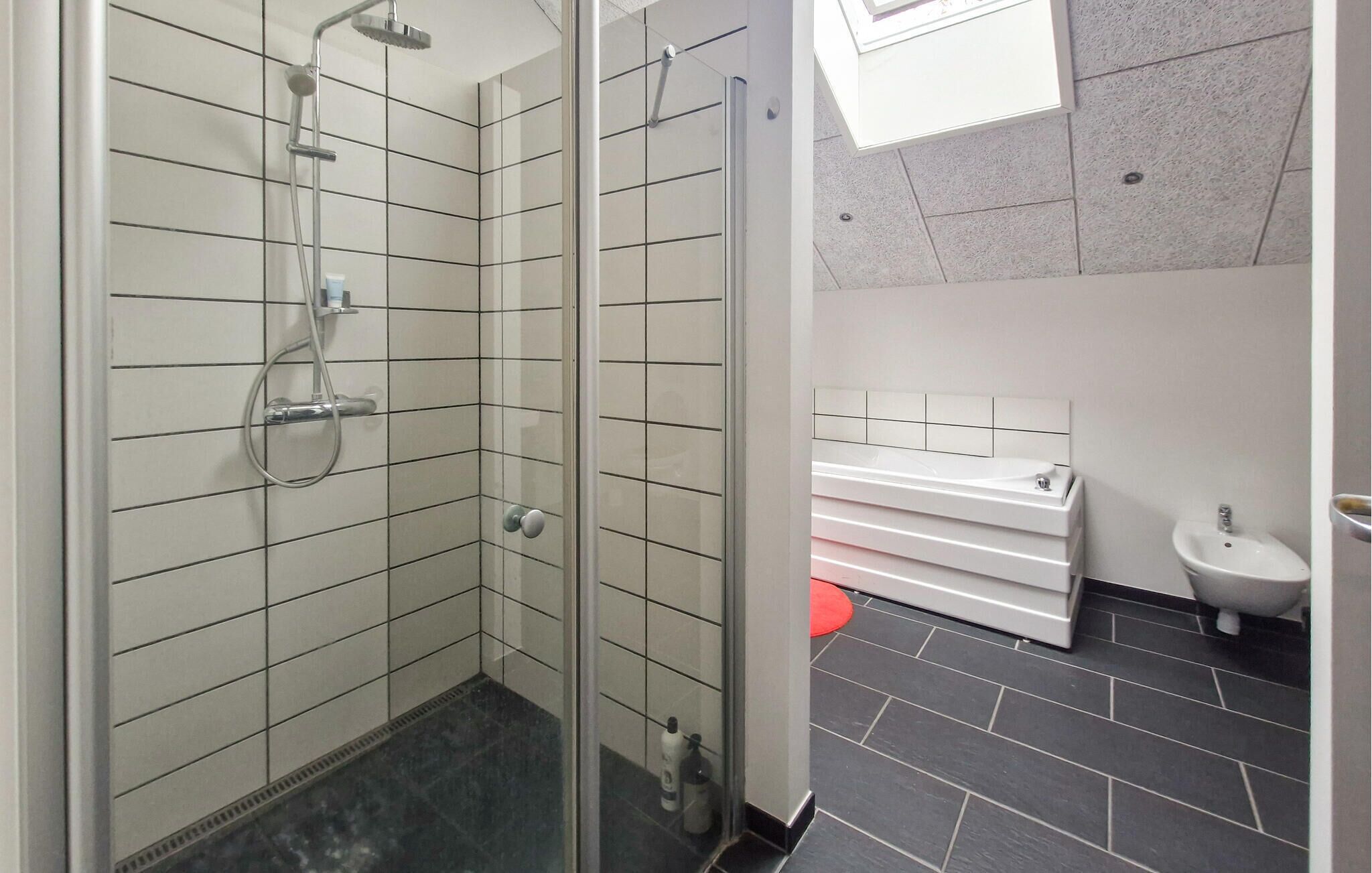 A modern bathroom with a glass-enclosed shower, a white sink, and a bidet.