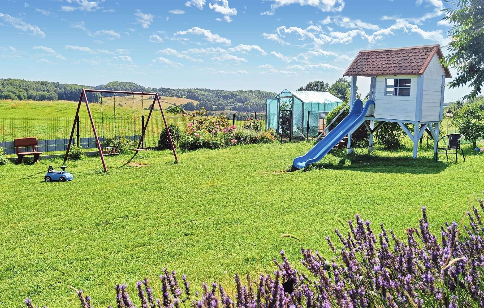A playground with swings, a slide, and a small house structure.