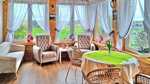 Una stanza accogliente con arredamento in legno, un tavolo da pranzo con tovaglia verde e sedie in vimini.