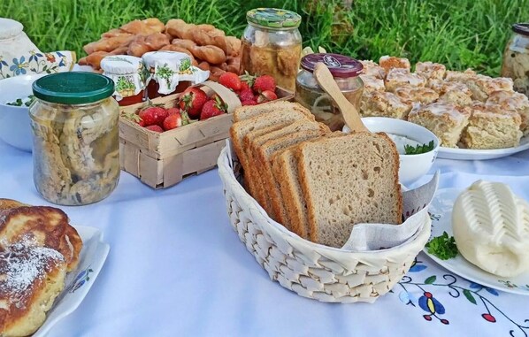 A picnic spread with various foods including bread, strawberries, and jars of preserves.