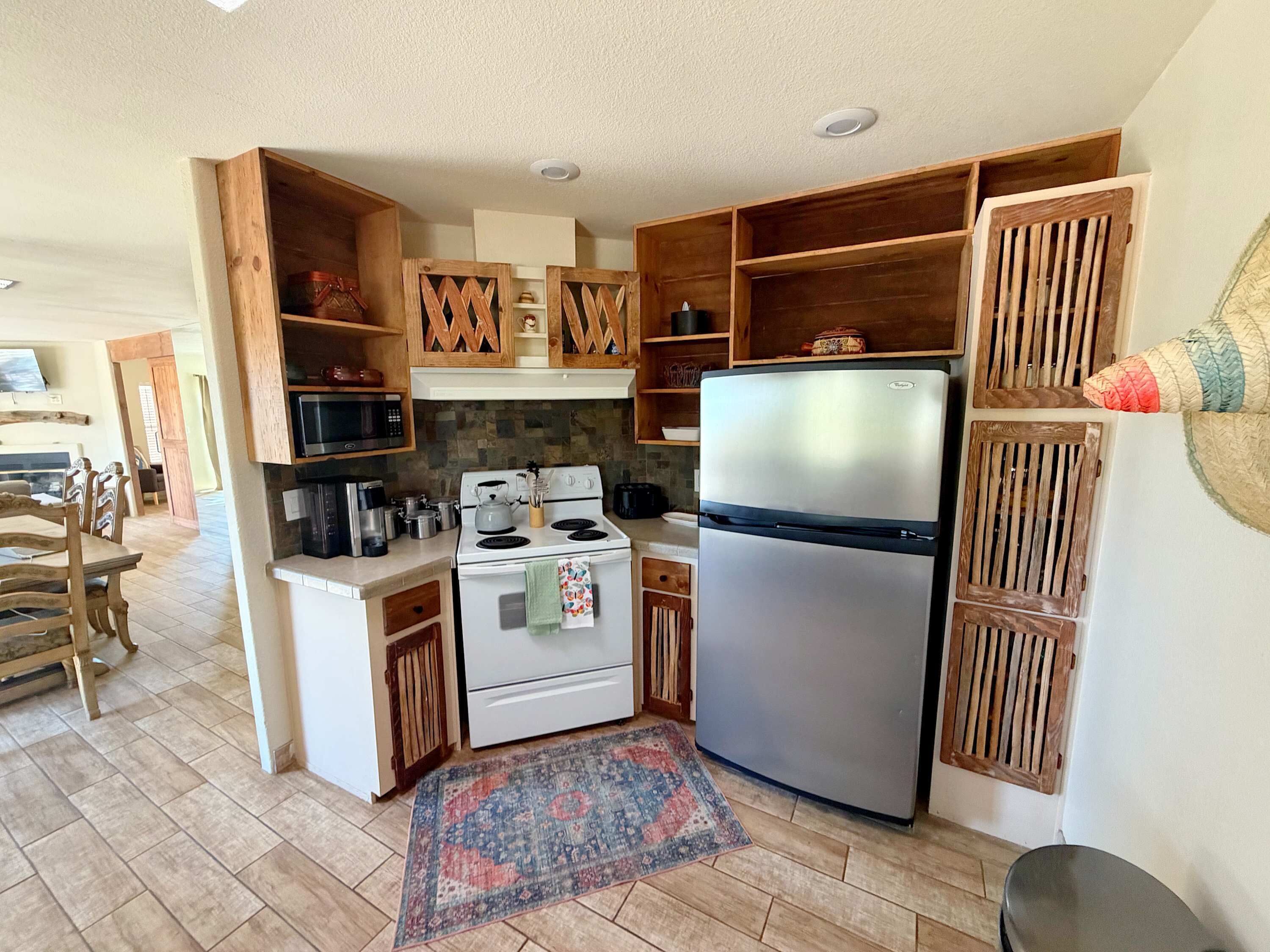 Une cuisine compacte avec des meubles en bois, un réfrigérateur en acier inoxydable, un four à micro-ondes et une cuisinière.