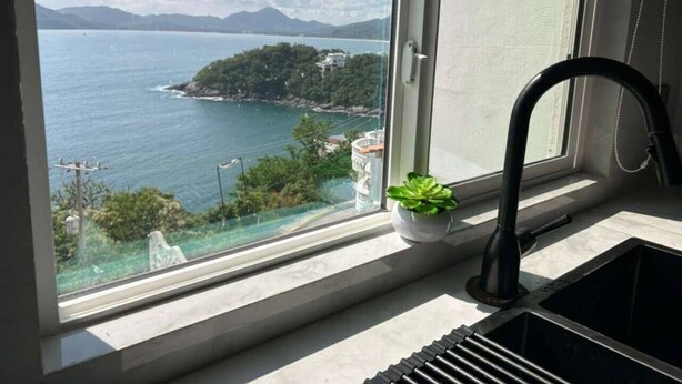 Una cucina con una finestra che si affaccia su un corpo d'acqua e un'isola in lontananza.