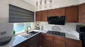 Una cucina moderna con mobili in legno, un fornello a gas, una cappa aspirante nera e una finestra con vista.