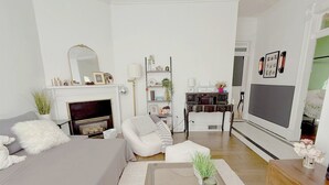 A modern living room with a fireplace, a sofa, a coffee table, and a TV. - Eclectic, Bright, & Spacious Retreat in the Heart of SLC (Salt Lake City)