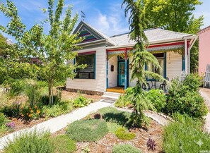 A residential house with a front porch, a small garden with various plants, and a clear sky. - Eclectic, Bright, & Spacious Retreat in the Heart of SLC (Salt Lake City)
