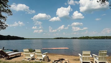 Private lakeside beach with dock, loungers, and peaceful water views