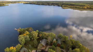 A lakeside property with cabins, a dock, and surrounding forest.