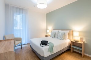 A hotel room with a bed, bedside tables, a chair, and a window with curtains. - Quality Aparthotel Nancy Zenith (Laxou)