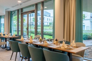 A restaurant with multiple tables set for dining, large windows offering a view of the outdoors, and a modern interior design. - Quality Aparthotel Nancy Zenith (Laxou)