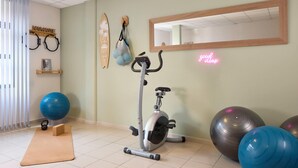 Een fitnessruimte met een hometrainer, yogamat, kettlebell en trainingsballen.