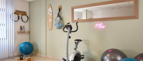 A fitness room with an exercise bike, yoga mat, kettlebell, and exercise balls.