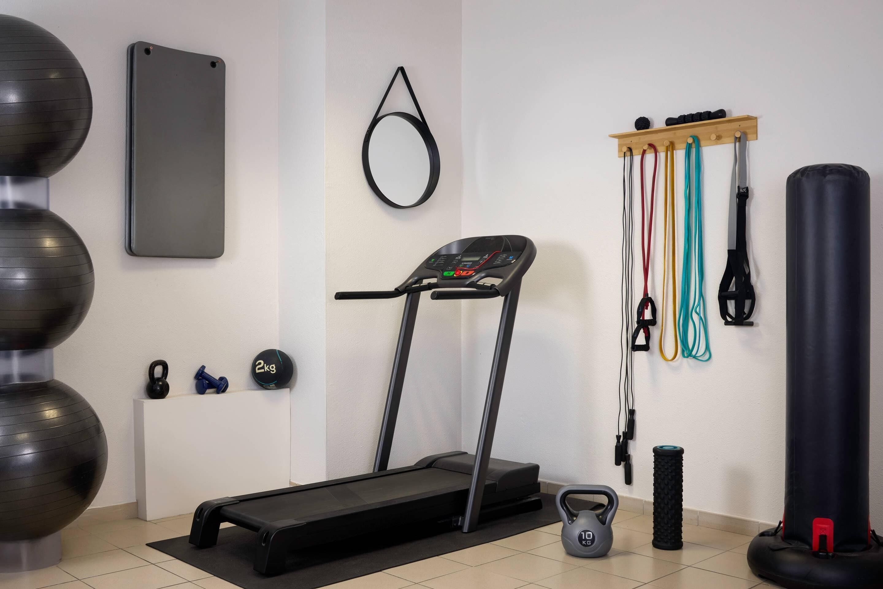 Uma academia em casa com esteira, halteres, faixas de resistência e bolas de exercícios.