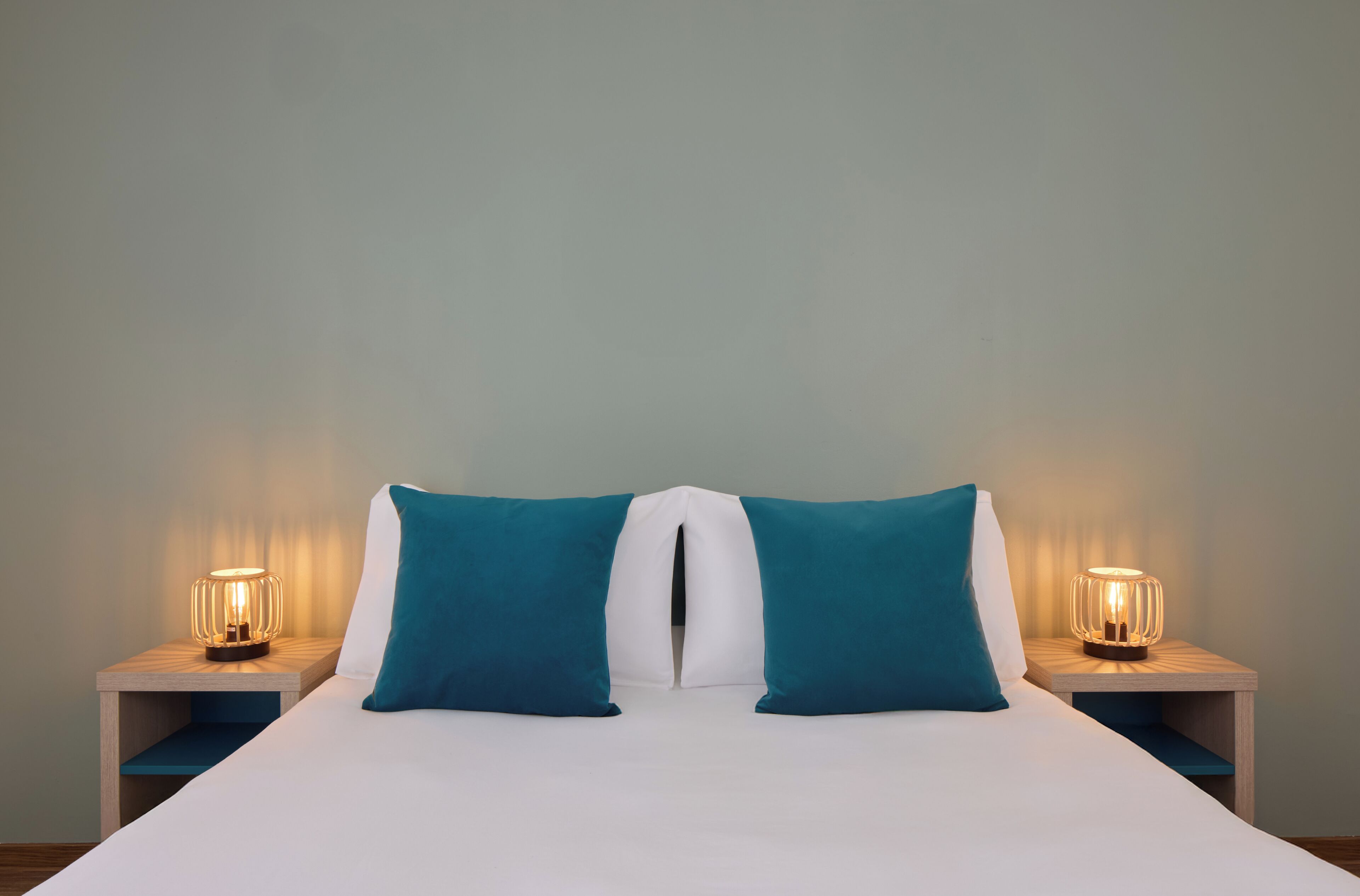 A bed with two pillows, a bedside table with a lamp, and a nightstand with a lamp.