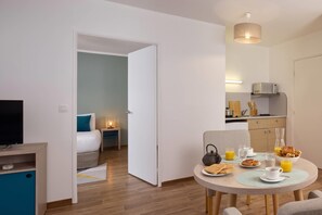 Een moderne hotelkamer met een bed, nachtkastje en een zithoek met ontbijt.