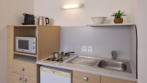 Une petite cuisine équipée comprenant un four à micro-ondes, une cuisinière, un évier et des placards en bois.