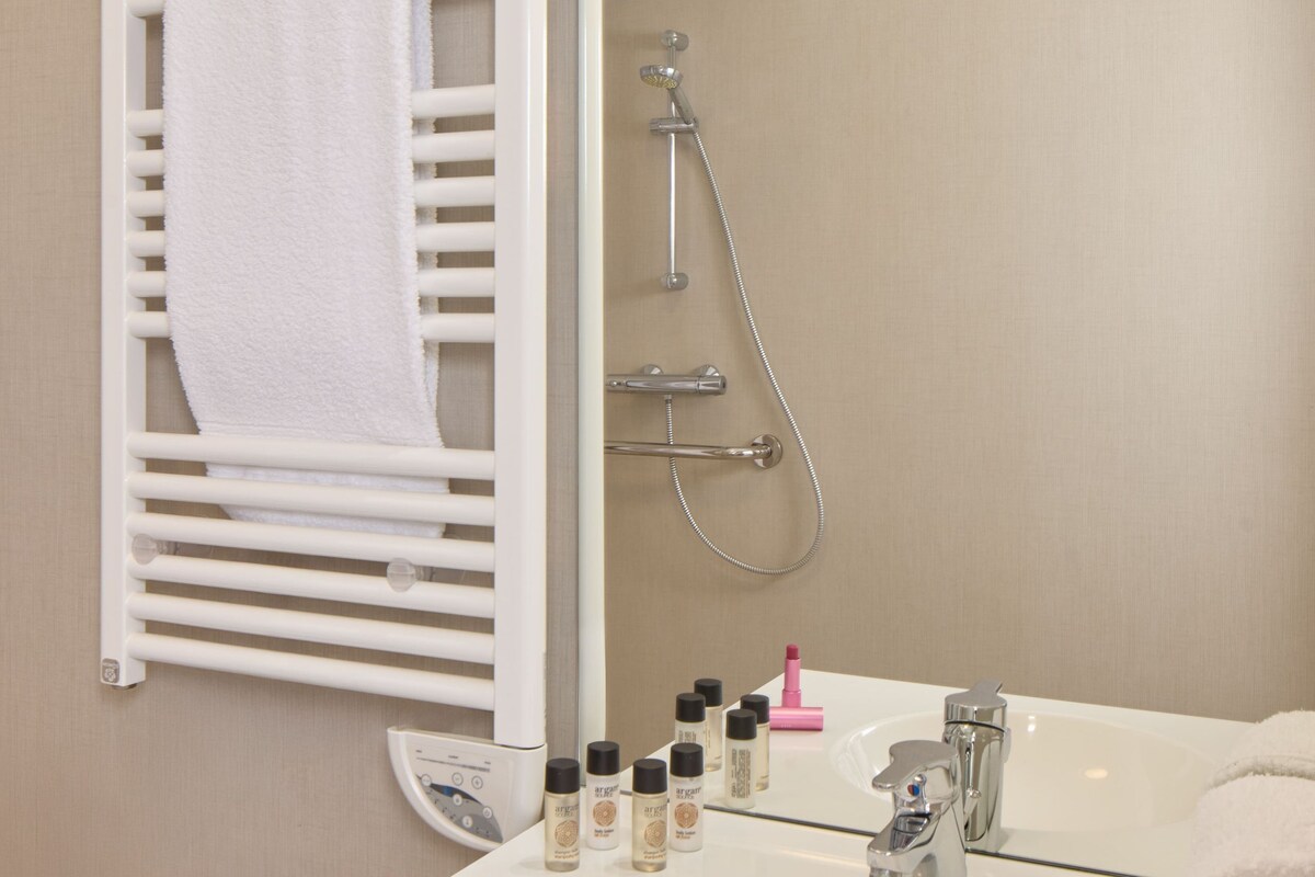 A bathroom with a white sink, a mirror, a towel rack, and a shower.