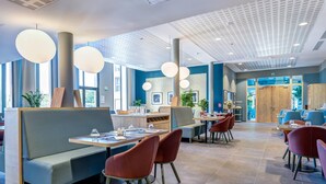 A modern restaurant with high ceilings, pendant lighting, and a mix of seating options including booths and tables. - Quality Aparthotel Morangis Orly (Morangis)