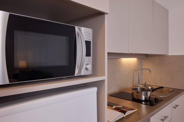 A compact kitchen with a built-in microwave, a sink, and a small countertop. - Quality Aparthotel Morangis Orly (Morangis)