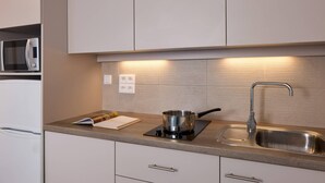 A modern kitchen with a built-in microwave, a stove, and a sink. - Quality Aparthotel Morangis Orly (Morangis)