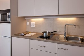 A modern kitchen with a built-in microwave, a stove, and a sink. - Quality Aparthotel Morangis Orly (Morangis)