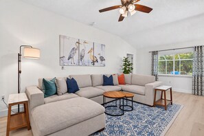 Ein modernes Wohnzimmer mit einem Ecksofa, einem Couchtisch, einer Stehlampe und Kunstwerken an der Wand.