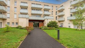 A multi-story residential building with balconies, a central entrance, and a well-maintained lawn. - Quality Aparthotel Reims - Les Capucins (Reims)
