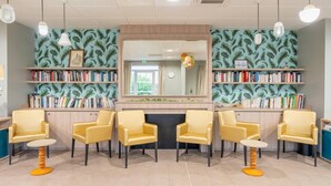 A room with a fireplace, bookshelves, and yellow chairs. - Quality Aparthotel Reims - Les Capucins (Reims)