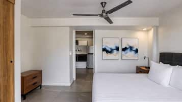 Un dormitorio con cama, mesita de noche, ventilador de techo y una obra de arte en la pared.