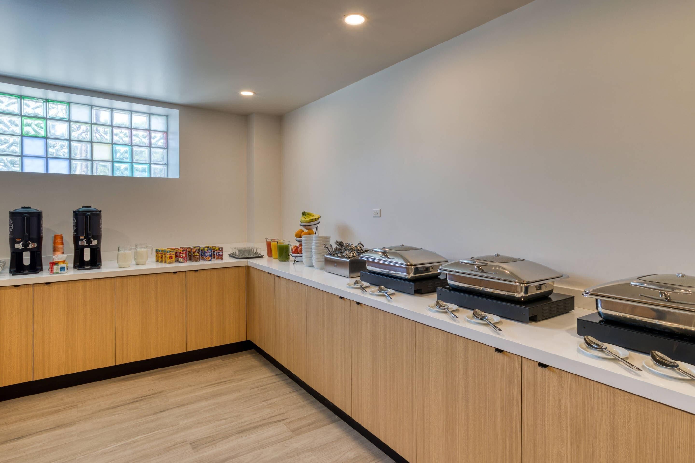 A modern kitchen with a white countertop, wooden cabinets, and a window with frosted glass.