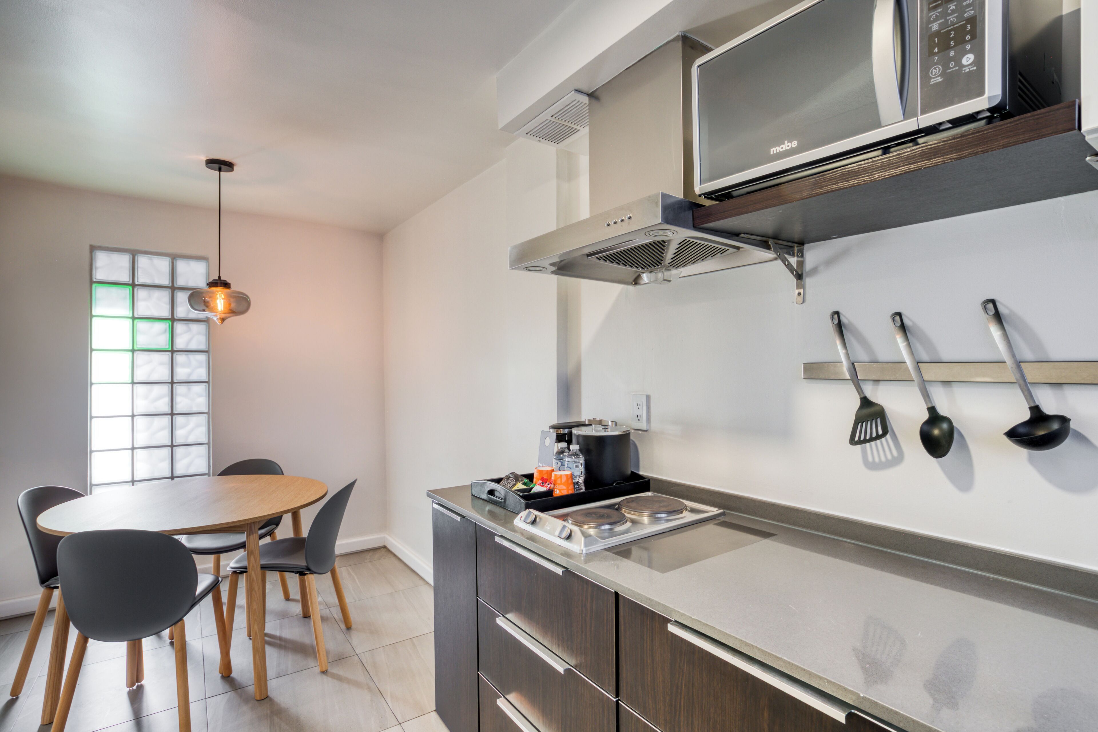 A modern kitchen with a microwave, stove, and hanging utensils.
