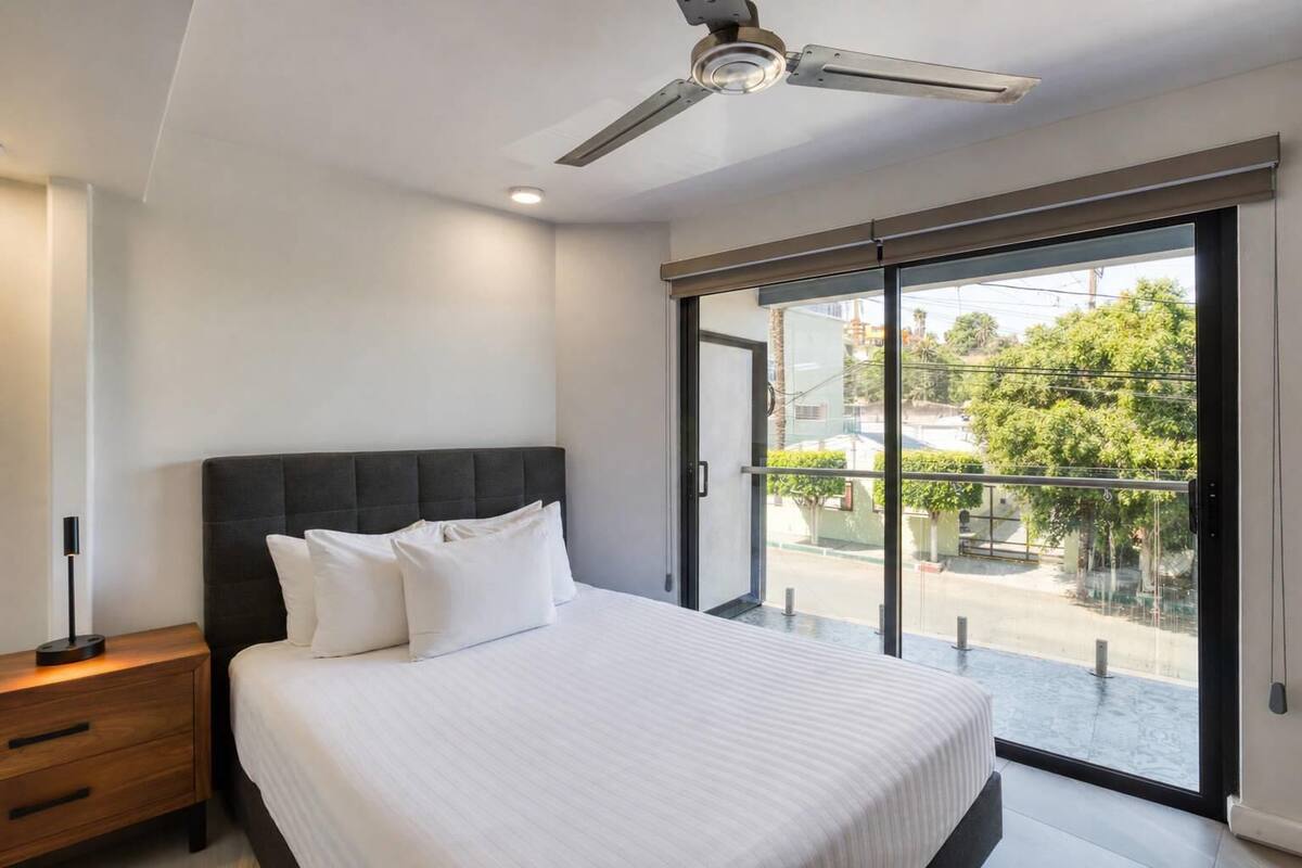 A bedroom with a bed, bedside table, and a ceiling fan.