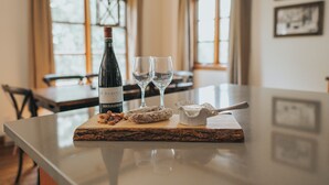 A table with a bottle of wine, two glasses, and some food items.