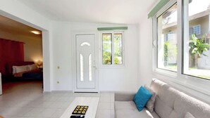 A bright living room with a sofa, a coffee table, and a door leading to another room. - Dani's House (Ialysos)