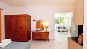 A hotel room with a bed, wooden wardrobe, dresser, and a kitchenette. - Dani's House (Ialysos)