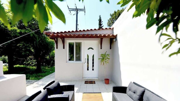 A small, white building with a tiled patio, two sofas, and a potted plant. - Dani's House (Ialysos)