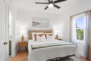 A neatly arranged bedroom with a bed, bedside lamps, a ceiling fan, and a window with curtains.