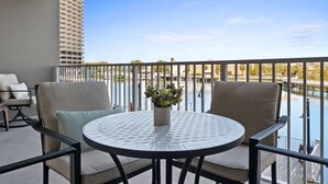 A balcony with two chairs and a table, a potted plant, and a view of a water body and buildings. - Lake Views, Resort Pools & Near the Beach | Laketown Wharf 114 (Panama City)
