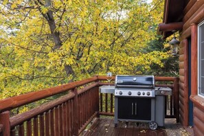 A wooden deck with a barbecue grill and a glass of wine.