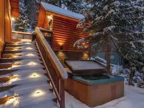 Eine Holzhütte mit Whirlpool und einer Treppe zu einer Terrasse.