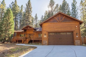 A wooden cabin with a porch, a garage, and a stone foundation.
